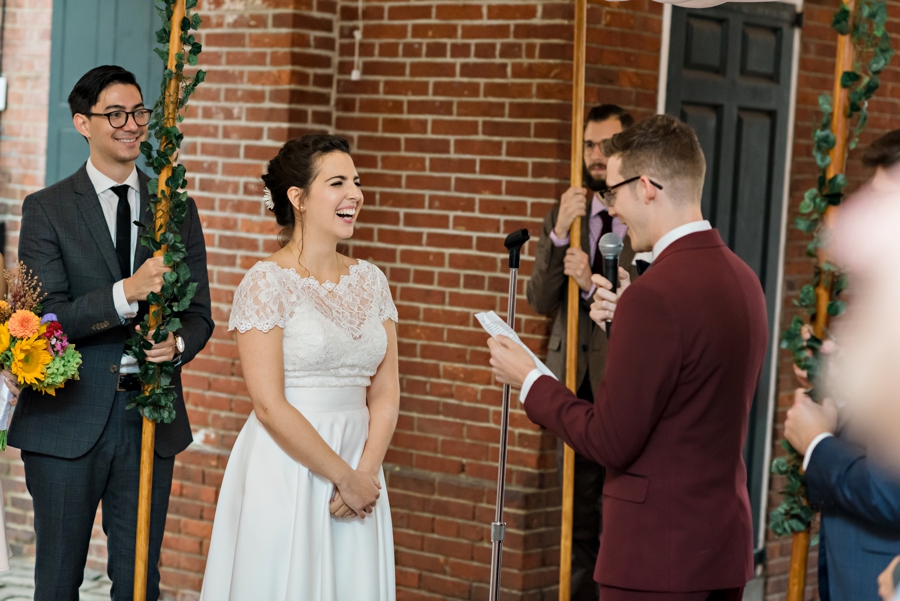 A bride laughing at the funny vows from her groom.